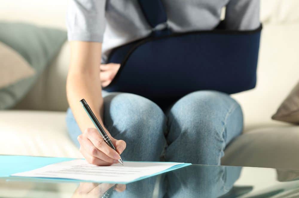 Image of a woman in a sling filling out paperwork