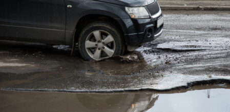 car passing over a pot hole