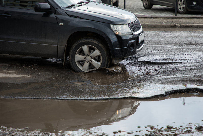 car passing over a pot hole