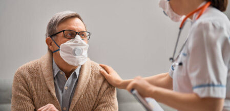nurse and elderly protected with medical masks against covid-19