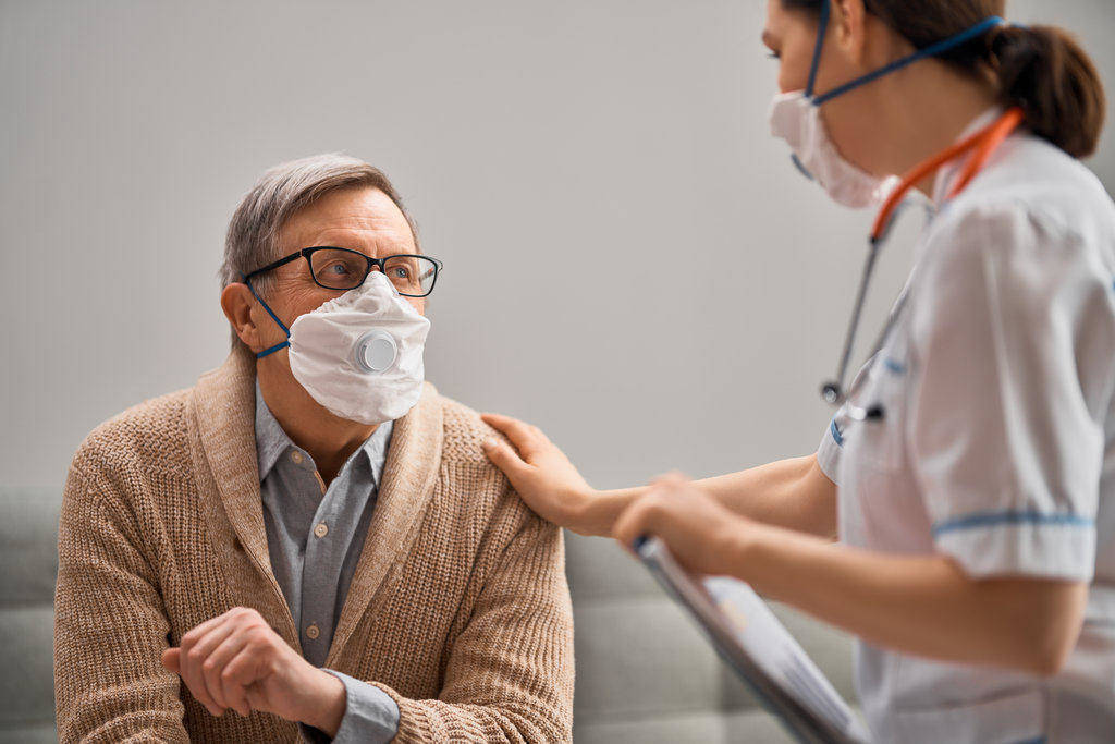 nurse and elderly protected with medical masks against covid-19