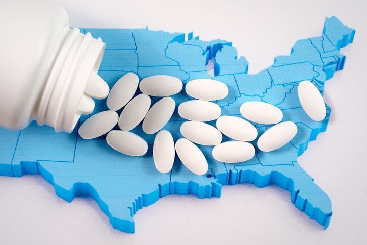 opioid tablets spilled out of container over a US map