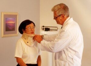 a woman getting fitted for a neck brace by her doctor