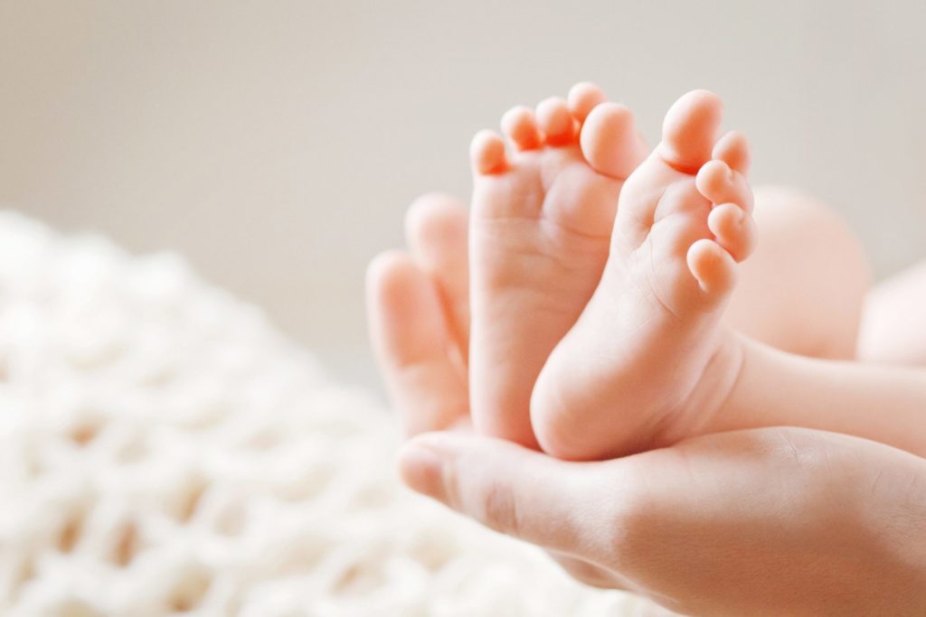 mother holding newborn baby feet