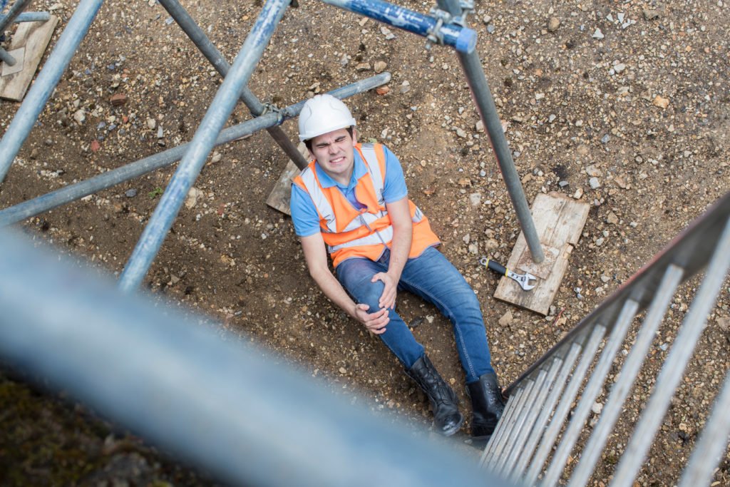 Construction worker holding leg after work accident