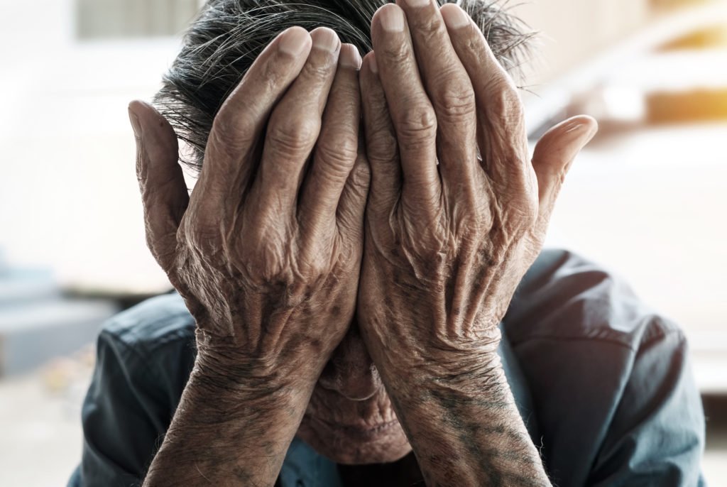 Elderly man puts palms to his head to represent his neglect in a nursing home