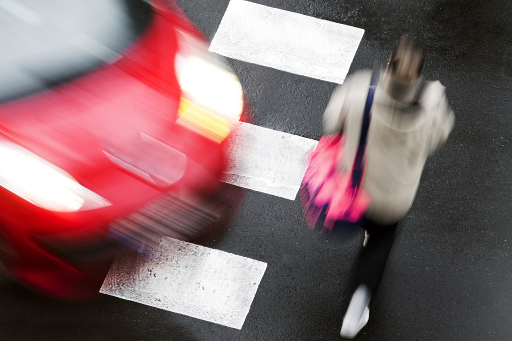 Woman crossing the road about to be hit by a car