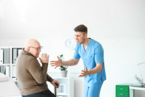 a male nurse is yelling at the elder man in a nursing home