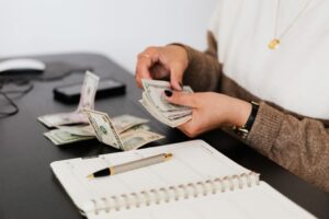 a woman counting dollar bill with pen documents