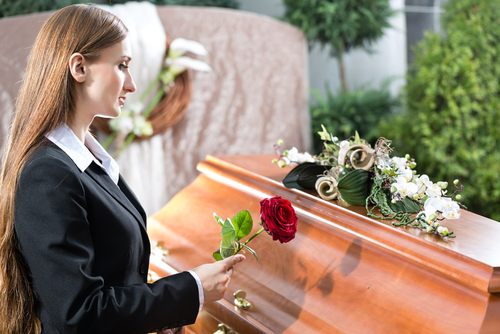 female laying flower on wrongful death victim's coffin.