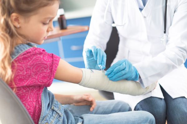 close-up of doctor preparing casted leg of a child