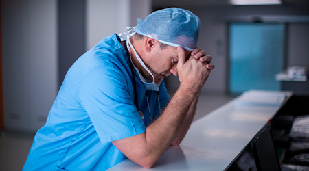 Doctor in scrubs with his head in his hands after making a medical error in a South Carolina hospital