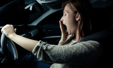 a woman yawning while driving at night