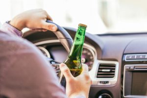 a driving man holding a bottle of liquor