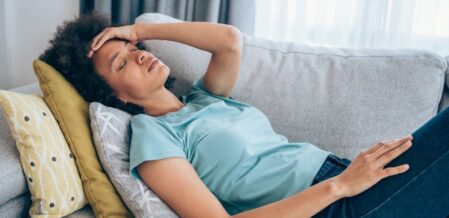 a woman laying on a couch holding her head