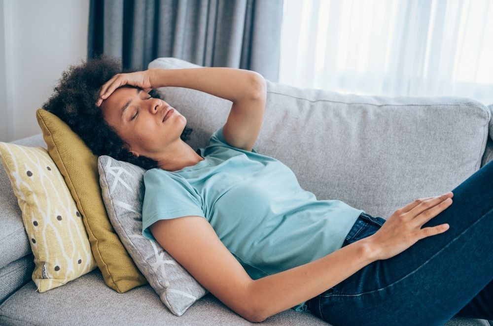a woman laying on a couch holding her head