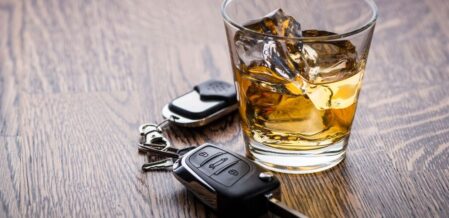 a glass of whiskey next to car keys