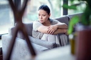 In grief. Blue joyless woman staring aside and hugging knees