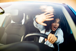 Mid adult woman driving and looking scared and surprised at the road in front of her.