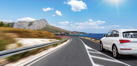 White car rushes along the road to the sea