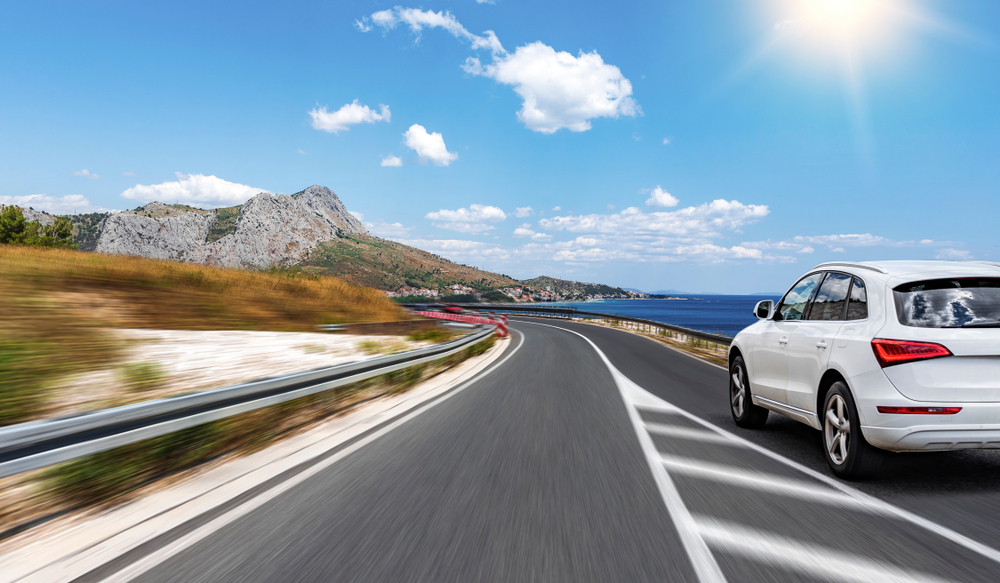 White car rushes along the road to the sea