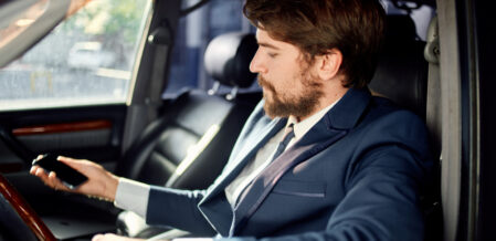 man in a suit sits behind the wheel of a car