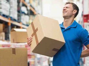warehouse worker having a backpain while holding in his one arm a big box