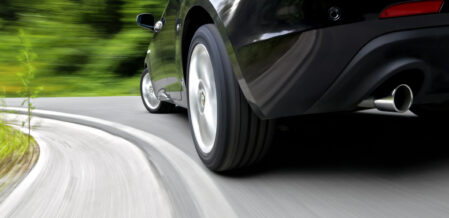 Low angle, rear wheel motion blur shot of a sports car driving fast in a curve
