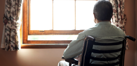 man in a wheelchair looking at a window
