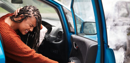 Image of a woman clutching her neck after a car crash