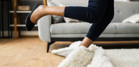 Image of a woman tripping on a rug in a living room