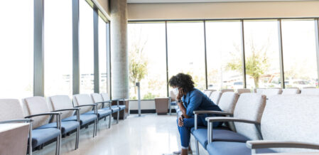 In the hospital waiting room, the distressed mid adult woman rests her head in her hands to think.