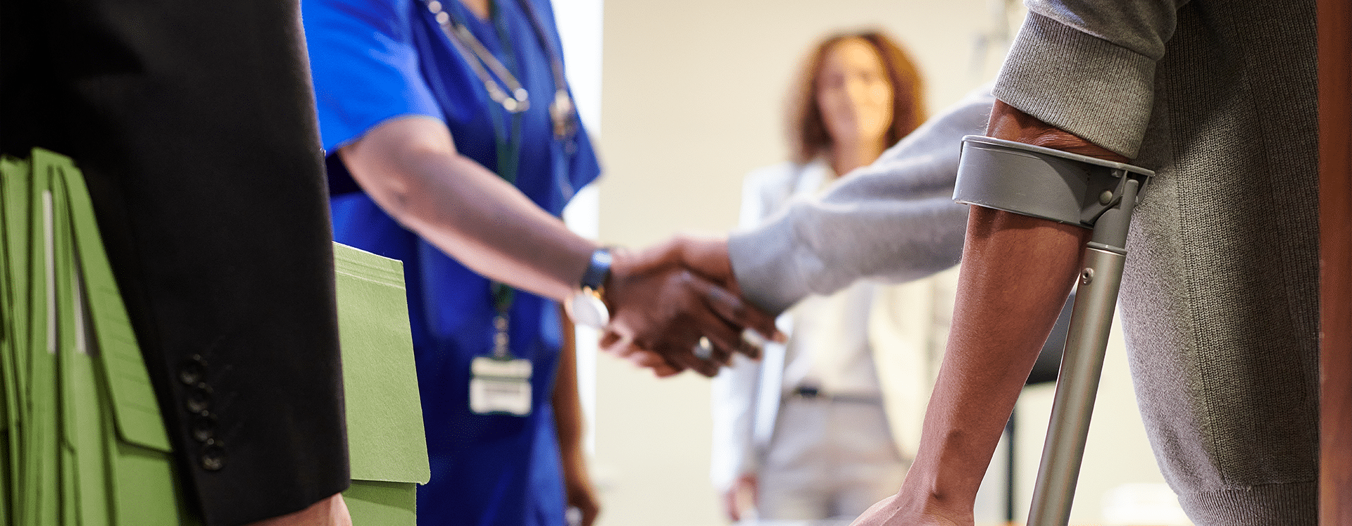 A person a crutches shaking hands with a doctor