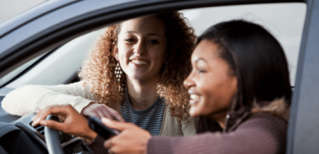 a passenger looking at the driver of a car who is texting
