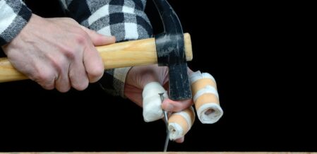 A man trying to hammer a nail but hits his finger
