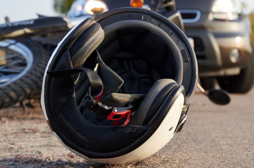 Image of a motorcycle helmet lying on the ground near a crashed bike