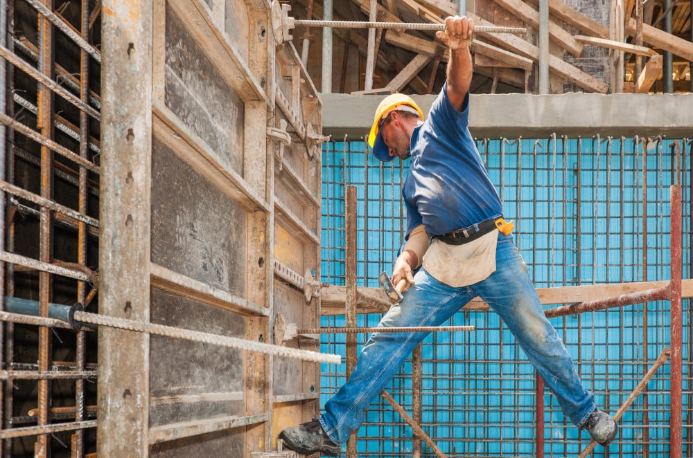 Image of a construction worker balanced in a precarious position