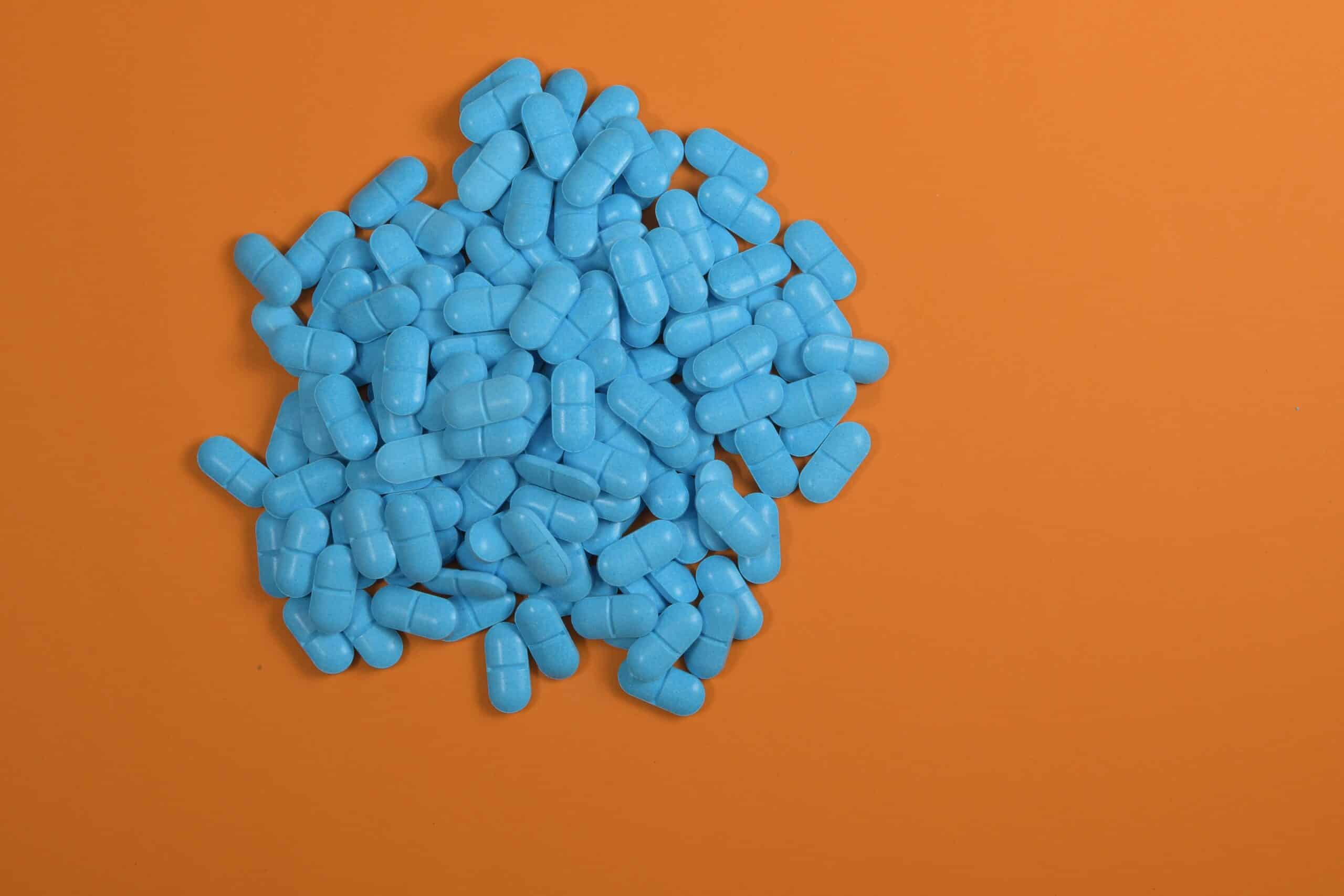 Orange background with a pile of blue pills