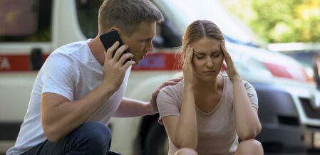 man on the phone with the police while girl is sitting on the curb
