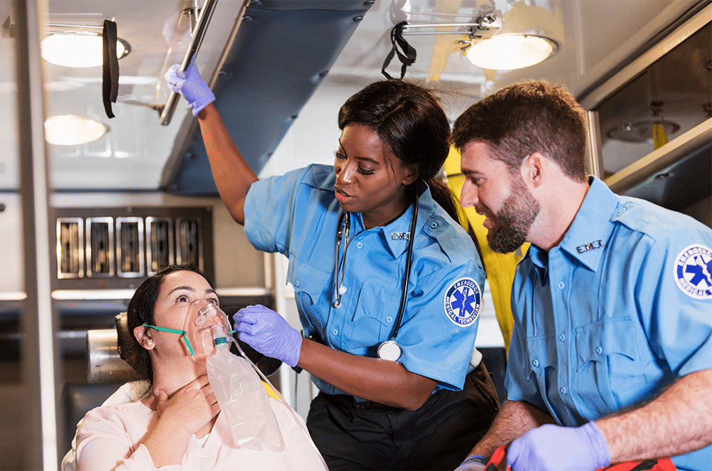 Image of two parademics tending to a woman in an ambulance