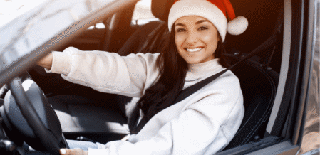 Image of a woman in a santa hat in the driver's seat of a car