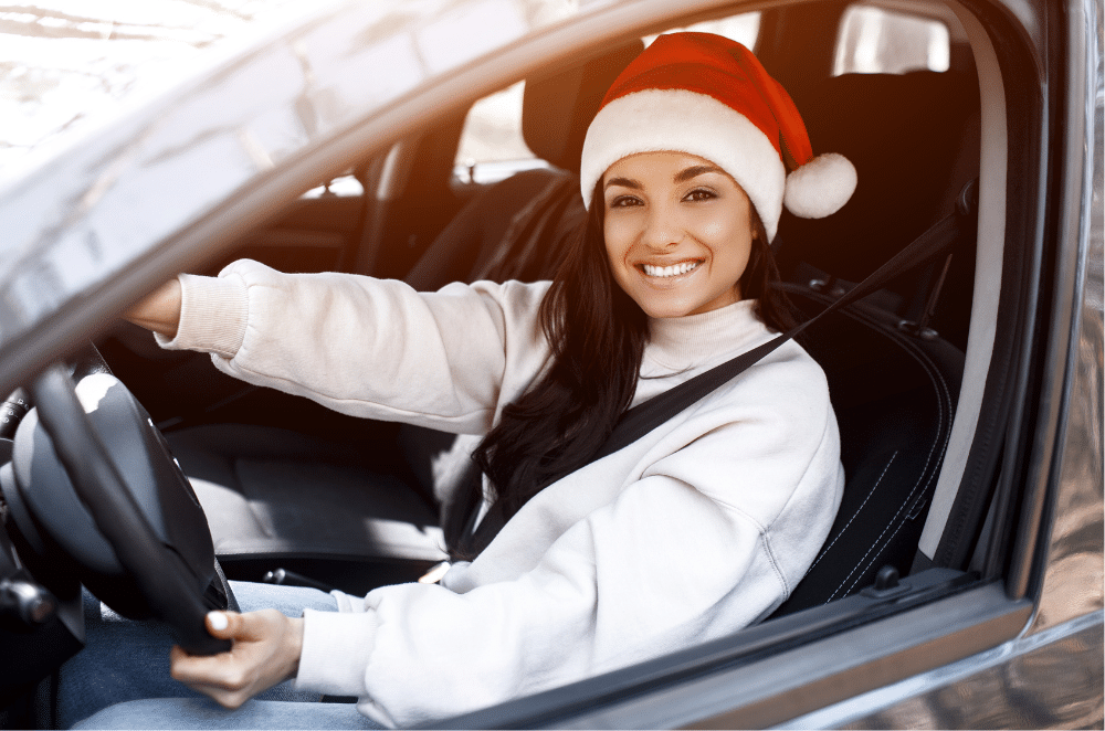 Image of a woman in a santa hat in the driver's seat of a car