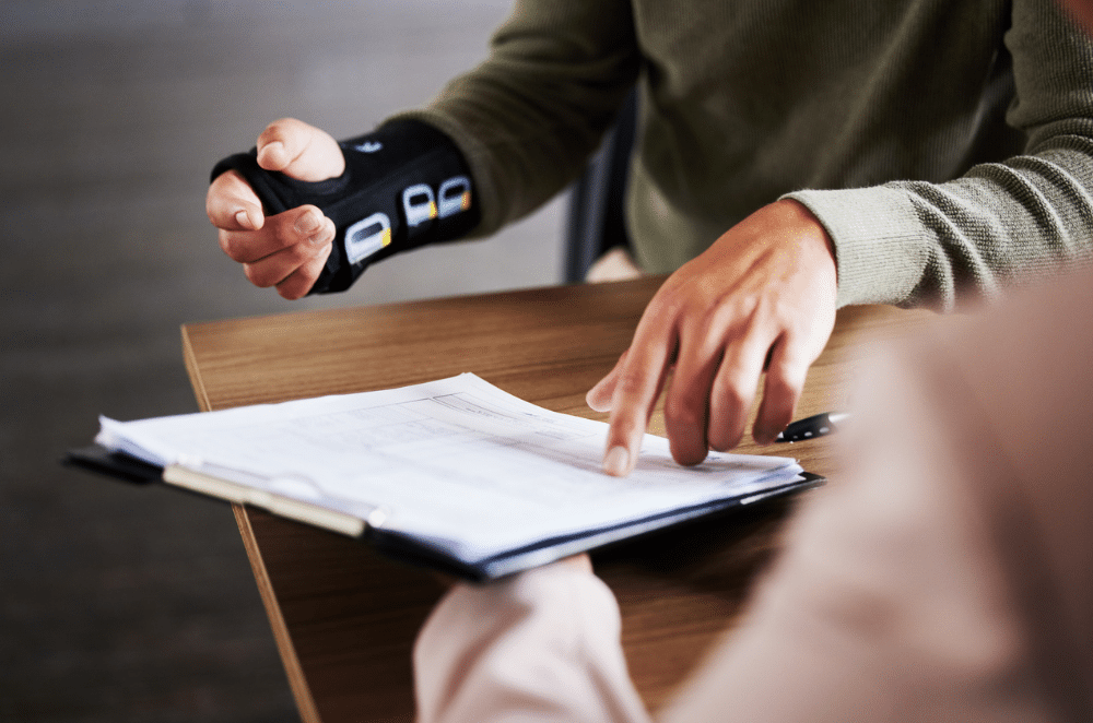 Image of someone with their arm in a brace looking over paperwork