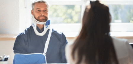Image of a man in a sling and neck brace speaking with a lawyer