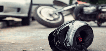 Image of a motorcycle helmet and motorcycle lying on the ground near a car