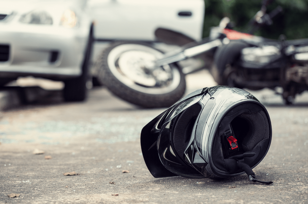 Image of a motorcycle helmet and motorcycle lying on the ground near a car