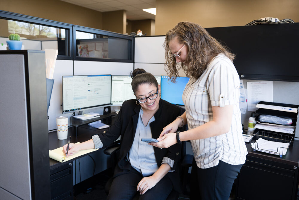 Joye Law Firm case managers look at a cell phone together in the Summerville office