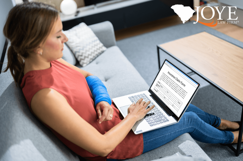 Image of a woman in a cast filing an insurance claim on her computer