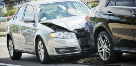 A car crash on the street with visibly damaged vehicles.