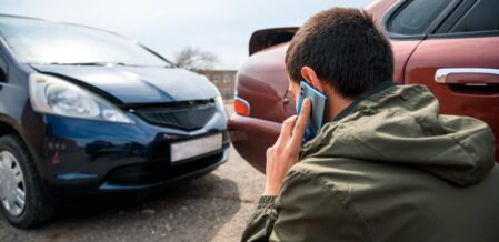 Person calls for assistance near two damaged cars after an accident, seeking legal or emergency help.